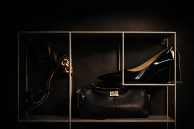 Escarpins vernis noirs et sac noir exposés sur une étagère